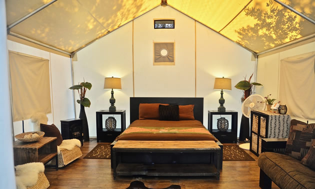 Inside of safari tent, with nice bed and furnishings. 