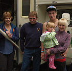 Grandparents, young couple and toddler stand beside their RV.