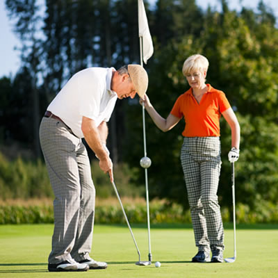 A man and a woman setting up a golf shot. 