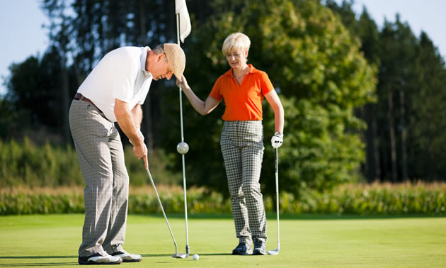 A man and a woman setting up a golf shot. 