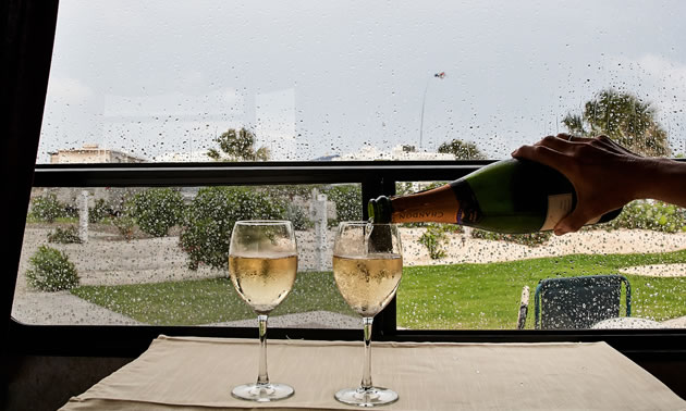 Bubbles in two wine glasses on a table in an RV mimic the rain on the window at Gulf Waters in Texas.