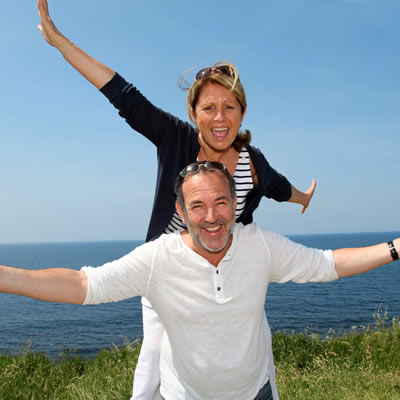 A couple posing in front of ocean scene. 