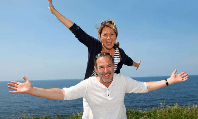 A couple posing in front of ocean scene. 