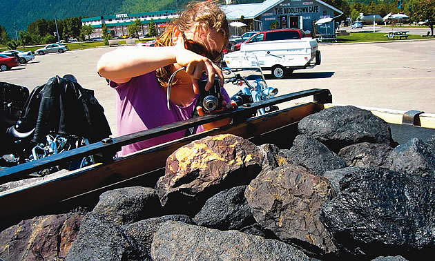 woman taking a photo of a truck full of coal in Sparwood BC