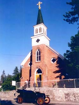 Rathdrum's St. Stanislaus Church is made of red bricks with a white steeple.