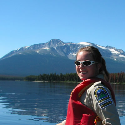 BC Parks student ranger in canoe on lake, looking over her shoulder at camera. 