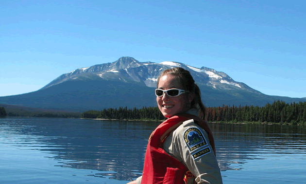 BC Parks student ranger in canoe on lake, looking over her shoulder at camera. 