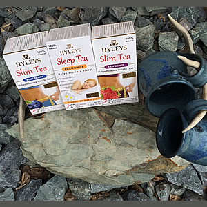 Three boxes of Hyleys tea displayed by two blue pottery mugs hanging on an antler on rocks