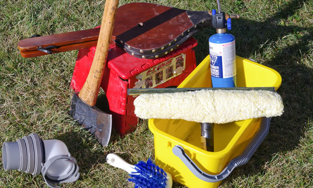 Shown are some of the author's essential items packed in his RV: a bucket, brush, bellows, an axe and a propane cylinder.