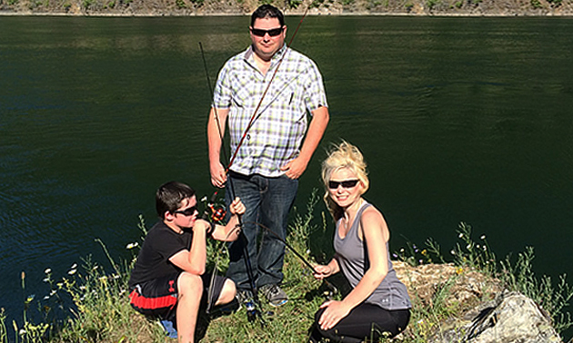 Eric Buckley, Will Buckley and Nicole Lind standing on a rockposing with fishing rods at the Pend d'Oreille River in British Columbia