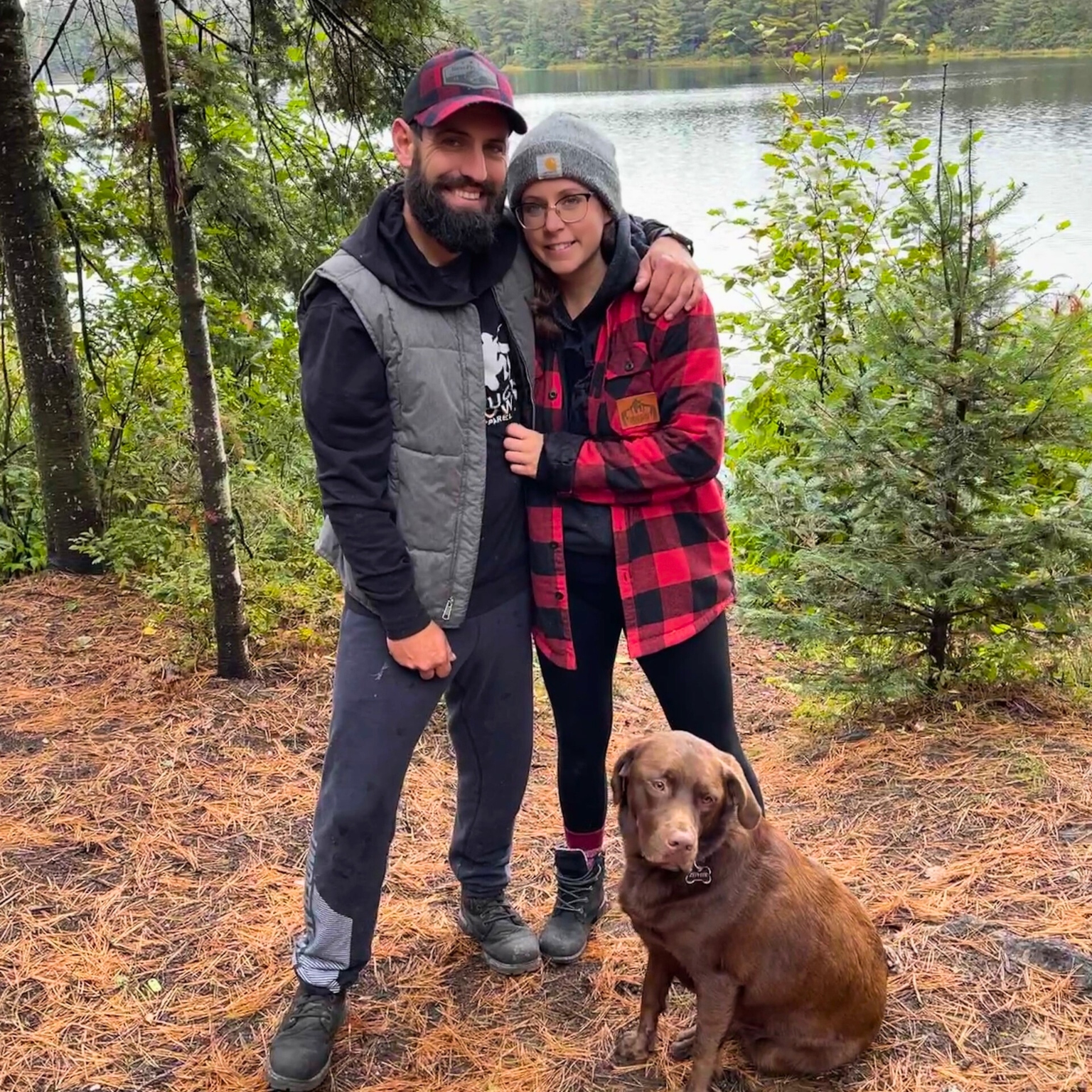 Amanda and Dustin in the woods with their chocolate lab dog
