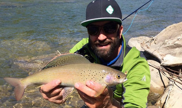 A crewman from Upstream Drift holding a fish caught in the Athabasca river.