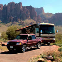 A red truck and brown RV are parked in front of Arizona's Superstition Mountains