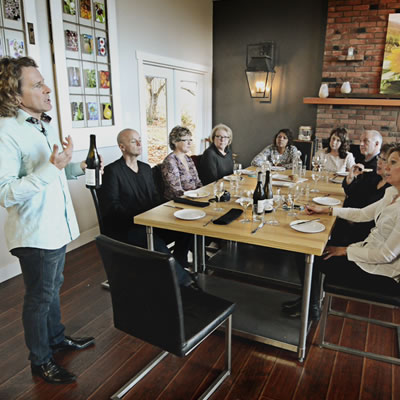 Ron Rocher is speaking to his tour guests, who are seated at tables at Backyard Farm Chef's Table.