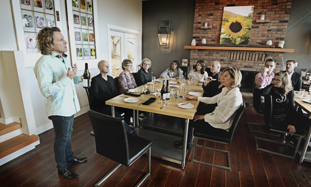 Ron Rocher is speaking to his tour guests, who are seated at tables at Backyard Farm Chef's Table.