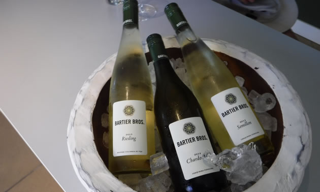 Bottles of white wines produced by Bartier Bros. are in a container on ice.
