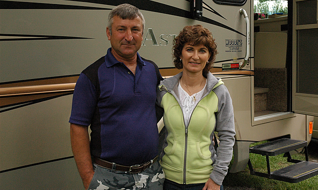 Middle-aged couple stand beside their motorhome.