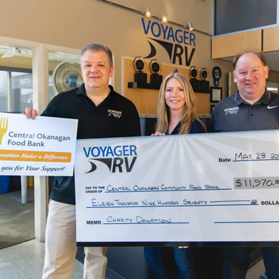 Voyager RV staff holding large cheques. 