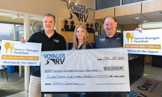 Voyager RV staff holding large cheques. 