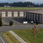 Gray Industrial building with rows of white garage doors  for accessing storage units.