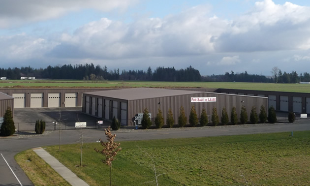 Gray Industrial building with rows of white garage doors for accessing storage units.