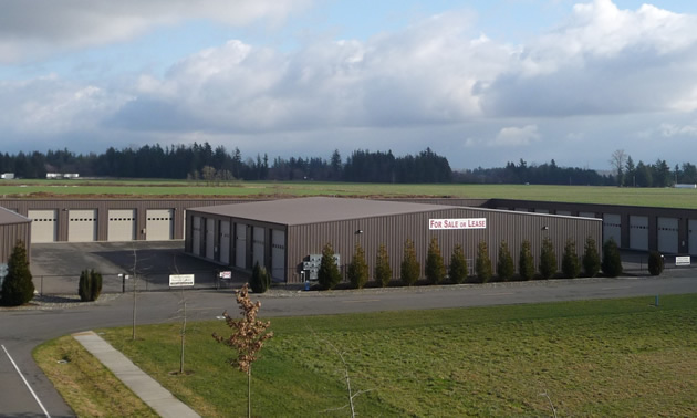 Gray Industrial building with rows of white garage doors  for accessing storage units.