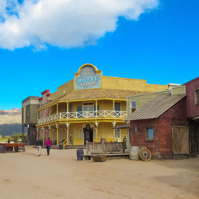 A streetscape of an Old Western town with a  large yellow hotel