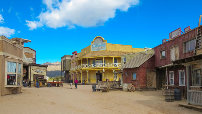 A streetscape of an Old Western town with a  large yellow hotel
