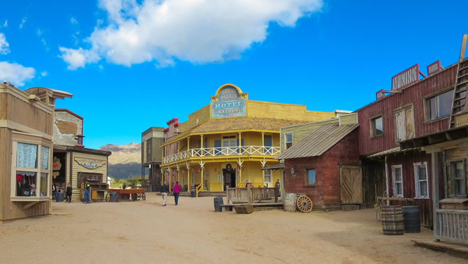 A streetscape of an Old Western town with a large yellow hotel