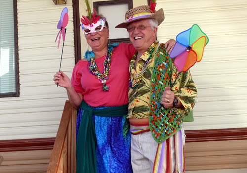 Stefan Sykut and Sharone O'Brien are dressed in bright Mardi Gras costumes.