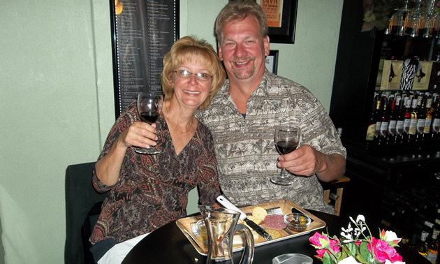 Sitting senior couple raise glasses of wine in a toast