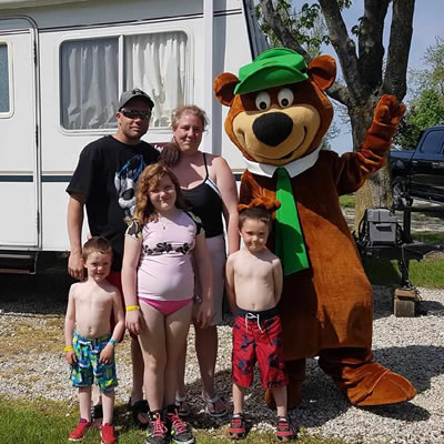 A family poses together with a Yogi Bear mascot. 