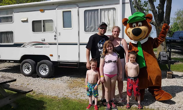 A family poses together with a Yogi Bear mascot. 