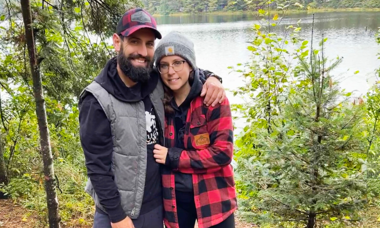 Amanda and Dustin in the woods with their chocolate lab dog