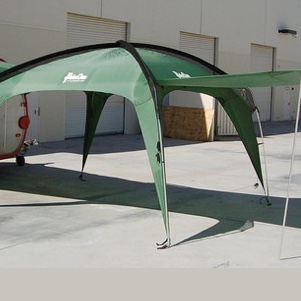 A green Cottonwood XLT shade shelter set up to join a teardrop trailer. 