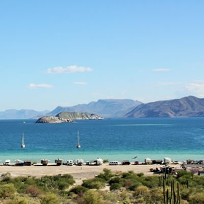 A vast expanse of white sand beach, with a turquoise-coloured ocean in the background and blue sky. 