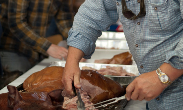 Author carves loin of whole smoked hog