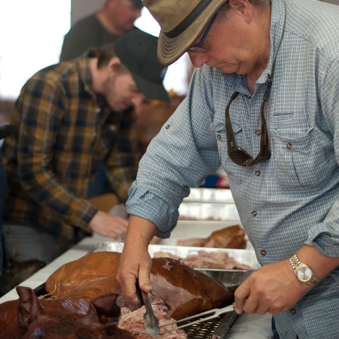 Author carves loin of whole smoked hog