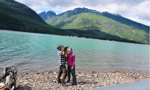 A couple on the beach holding their german shepherd