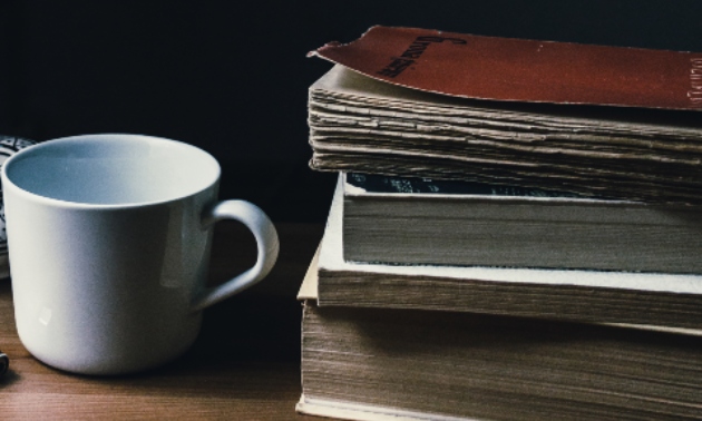 A coffee cup next to a stack of books