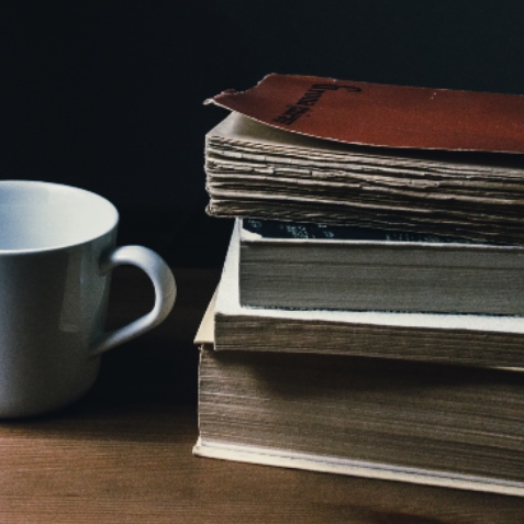 A coffee cup next to a stack of books