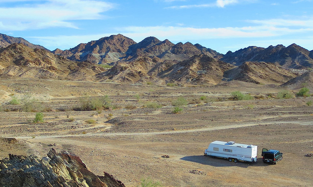 rv in the middle of a field with mountains around it