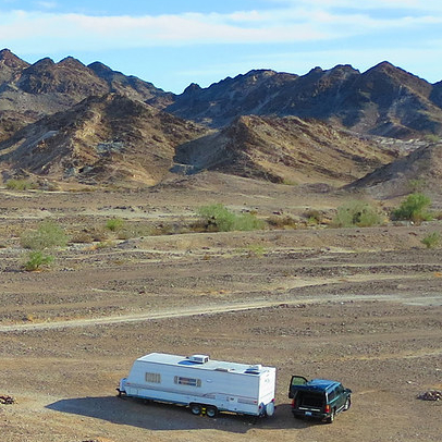 rv in the middle of a field with mountains around it