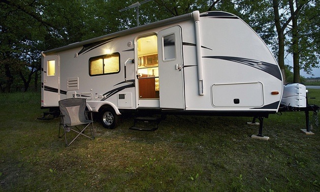 RV trailer parked near trees with no connections.