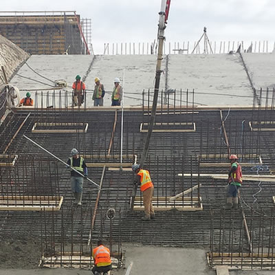 Workers working on steel beamed construction foundation.   