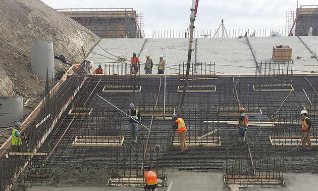 Workers working on steel beamed construction foundation.   