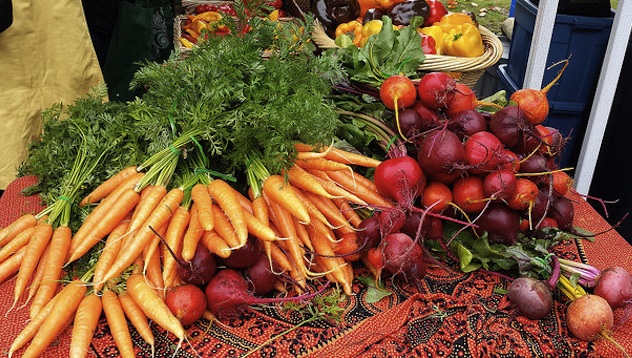 A colourful display of vegetables, carrots, beets, green, red and yellow peppers on a table. 