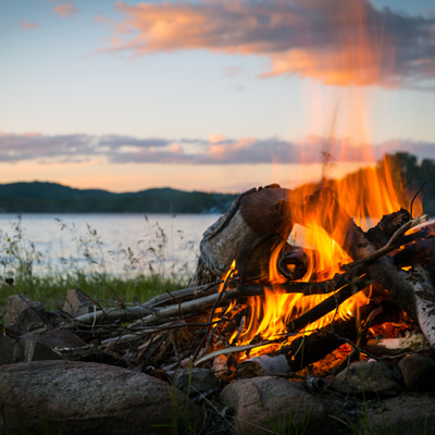 Close-up picture of campfire with sunset in the background. 