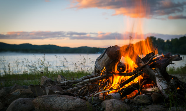 Close-up picture of campfire with sunset in the background. 