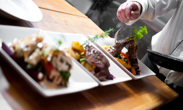 a chef plating three dishes with gourmet food